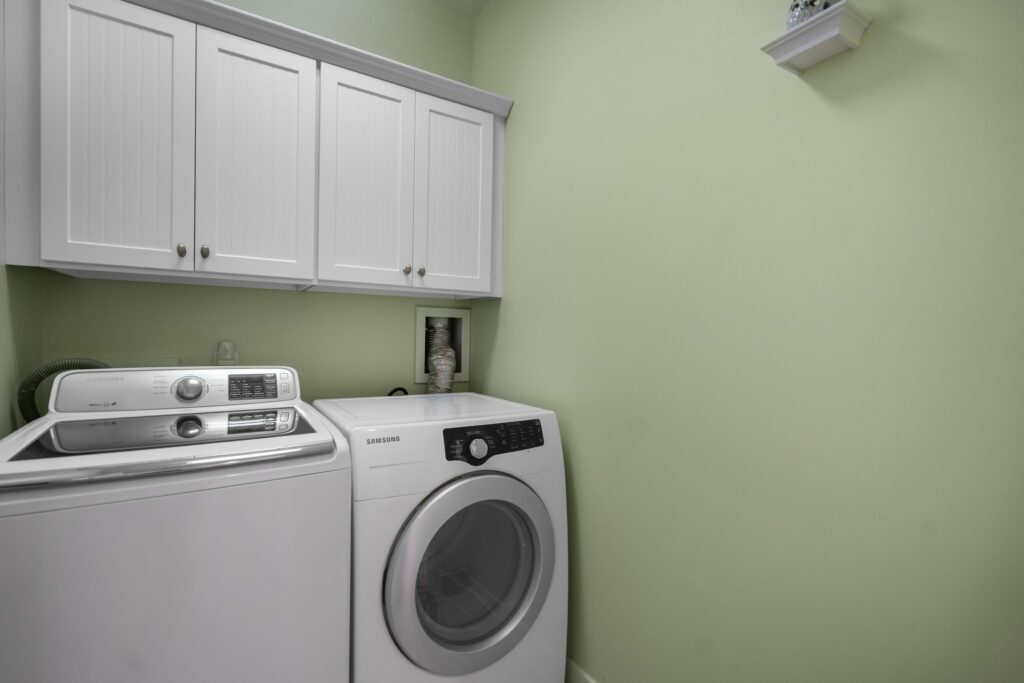 Inside of the laundry room. Beachy green walls. White washer and dryer machine against a wall